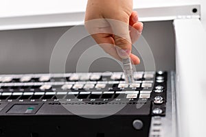 IT consultant connects network cable into switch in datacenter.