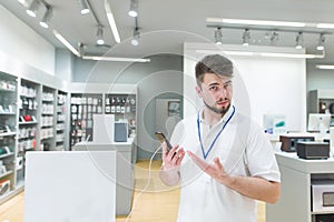 Consultant is in the electronics store and recommends the smartphone in his hands