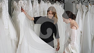 The consultant girl shows the wedding dress to the future bride. Wedding salon.