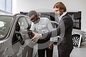 Consultant provides all information about new car using clipboard to male client