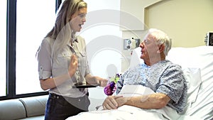 Consultant Talks To Senior Male Patient In Hospital Room