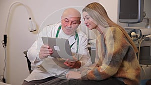 Consultation of an endocrinologist and a young girl. An experienced doctor shows laptop.