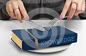 Consume knowledge concept, hands cut book on plate photo