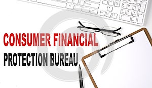 CONSUMER FINANCIAL PROTECTION BUREAU text written on the white background with keyboard, paper sheet and pen