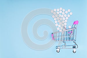 Consumer`s basket on a blue medical background in which white pills fall. Ð¡oncept of increasing medication.