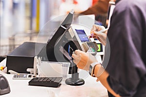 Consumers women signing on a touch screen of credit card sale transaction machine at supper market.