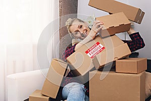 Consumerism concept - happy woman with cardboard boxes at home after shopping