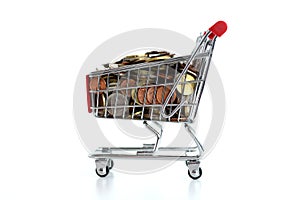 Consumerism concept with shopping trolley full of coins on white background