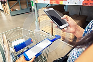 Consumerism Shopping and Technology Communication Concept, Close-Up Woman Hand is Using Mobile Phone Communicating While Products 