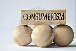 CONSUMERISM - word on a wooden block on a white background with wooden balls