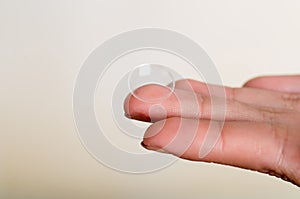 Contact lens on finger on gray background