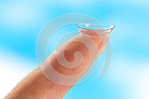 Contact lens on finger tip blue background