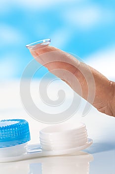 Contact lens on finger tip blue background