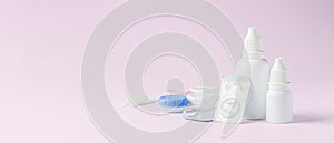 Contact lens, solution bottle and eye drops with box on light pink background