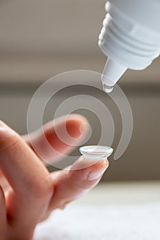 Contact lense cleaning on finger to correct nearsightedness and blurred vision eyesight by optician or oculist