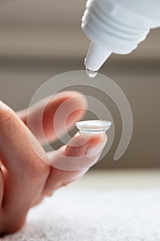 Contact lense cleaning on finger to correct nearsightedness and blurred vision eyesight by optician or oculist