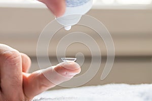 Contact lense cleaning on finger to correct nearsightedness and blurred vision eyesight by optician or oculist