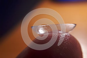 Contact lense on finger tip, macro. Contact lenses macro close up. Man holding lens on finger. Customer, patient or eye doctor,