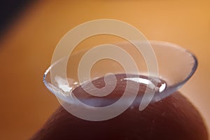 Contact lense on finger tip, macro. Contact lenses macro close up. Man holding lens on finger. Customer, patient or eye doctor,