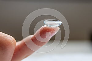 Contact lense on finger to correct nearsightedness and blurred vision eyesight by optician or oculist is to handle with hygiene