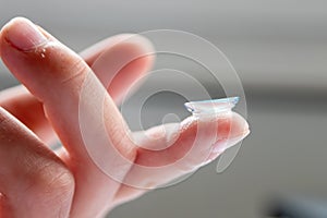 Contact lense on finger to correct nearsightedness and blurred vision eyesight by optician or oculist is to handle with hygiene