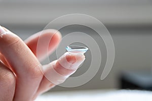 Contact lense on finger to correct nearsightedness and blurred vision eyesight by optician or oculist is to handle with hygiene