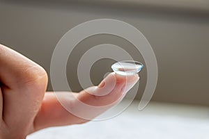 Contact lense on finger to correct nearsightedness and blurred vision eyesight by optician or oculist is to handle with hygiene