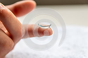 Contact lense on finger to correct nearsightedness and blurred vision eyesight by optician or oculist is to handle with hygiene