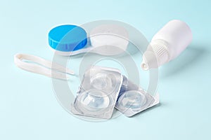 Contact lenses and accessories with eye drops on blue background