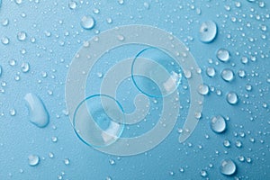 Contact lenses on blue background with water drops