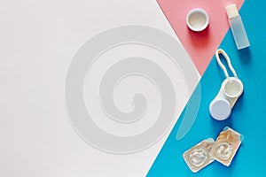 Contact lenses, case and accessories on pink, blue and white background. Eye health and care, eyesight and vision, ophthalmology