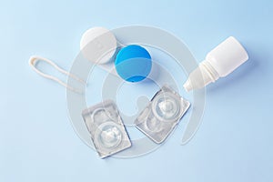 Contact lenses and case with eye drops on blue background