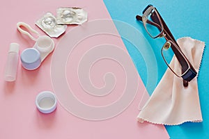 Contact lenses, case, glasses and accessories on pink and blue background. Eye health and care, eyesight and vision, ophthalmology