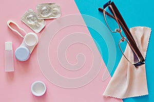 Contact lenses, case, glasses and accessories on pink and blue background. Eye health and care, eyesight and vision, ophthalmology