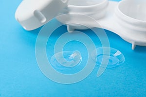 Contact lenses and case on light blue background, closeup