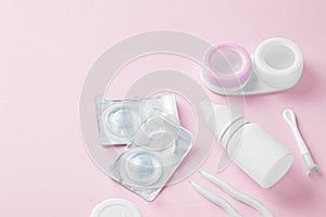 Contact lenses with container, eye drop and accessories on pink background