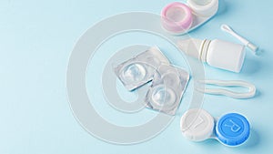 Contact lenses with container, eye drop and tweezer on blue background