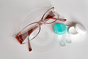 Contact lenses with a container and glasses on a white background. View from above. The topic of medicine and health