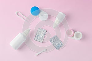 Contact lenses with container, solution bottle and accessories on pink background