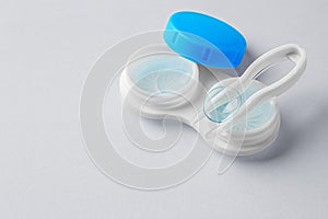 Contact lenses with container and tweezer on gray background