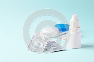 Contact lenses with eye drops and accessories on blue background