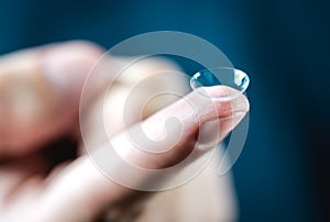 Contact lenses macro close up. Man holding lens on finger.