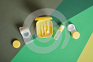 Contact lenses set with saline in bottle, tweezers, plastic case with solution on blue background with copy space