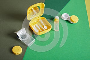 Contact lenses set with saline in bottle, tweezers, plastic case with solution on blue background with copy space