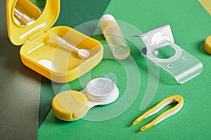 Contact lenses set with saline in bottle, tweezers, plastic case with solution on blue background with copy space