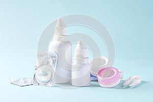 Contact lenses, solution bottle and eye drops with accessories on blue background