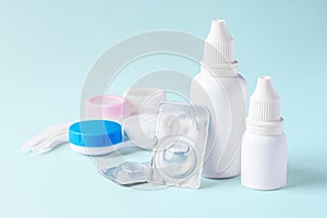 Contact lenses, solution and eye drops with cases on light blue background