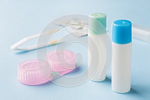 Contact lenses, tweezers and a container for storing lenses, containers for solution and moisturizing drops. Close up. Selective