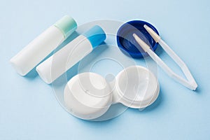 Contact lenses, tweezers and a container for storing lenses, containers for solution and moisturizing drops. Close up. Selective