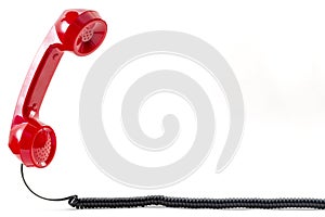 Contact us concept and floating phone receiver with a vintage red telephone handset floating above the curly cable isolated on